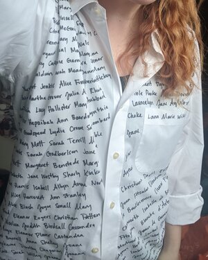 Picture of a woman wearing a white shirt with dozens of women's names written on it